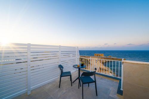 a balcony with two chairs and a table and the ocean at Salini Suites in Żebbuġ