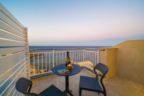 a table and chairs on a balcony with the ocean at Salini Suites in Żebbuġ