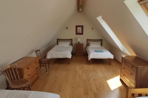 a attic room with two beds and a staircase at Spacious Luxury barn conversion - next to Tarka Trail cycle path in Great Torrington