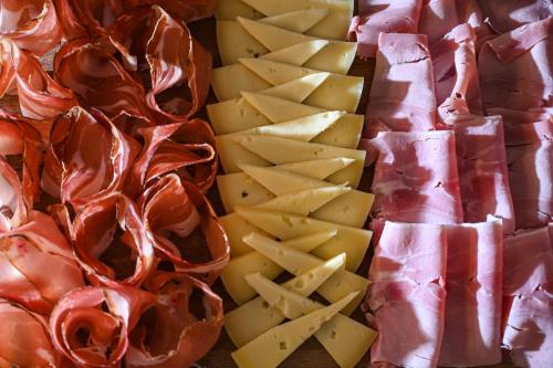 a pile of cheese and bacon and meat and cheese at Rifugio Cereda in Fiera di Primiero