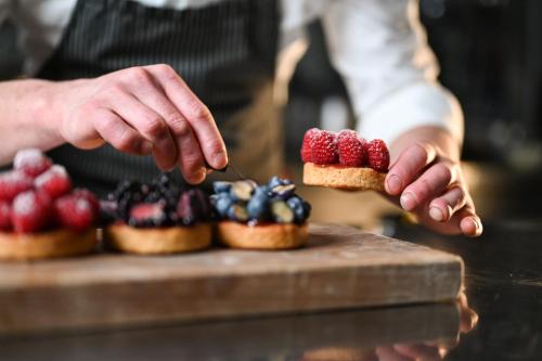 a man holding a piece of food with berries on it at Rifugio Cereda in Fiera di Primiero