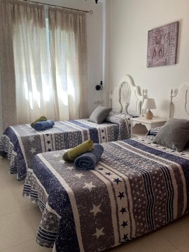 a bedroom with three beds with blankets on them at Apartamento Plata Real in Sanlúcar de Barrameda