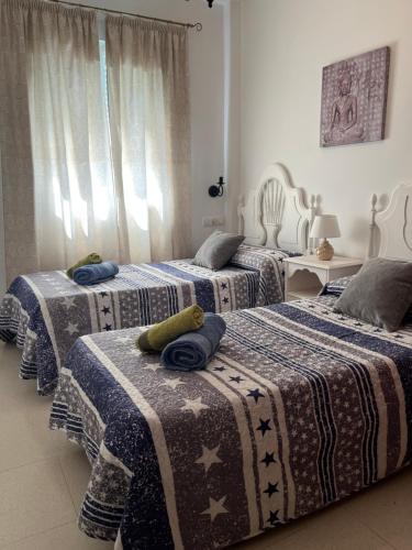 1 dormitorio con 3 camas con mantas en Apartamento Plata Real, en Sanlúcar de Barrameda