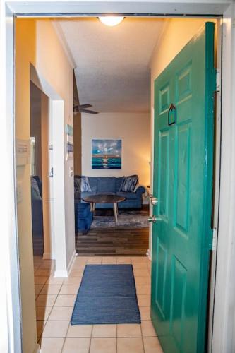 a hallway with a green door and a living room at 2 BR Condo W/ Golf Cart & Pool (Pet-Friendly) in Myrtle Beach