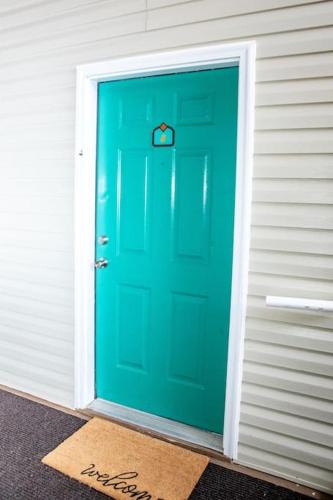 a green door with a welcome mat in front of it at 2 BR Condo W/ Golf Cart & Pool (Pet-Friendly) in Myrtle Beach