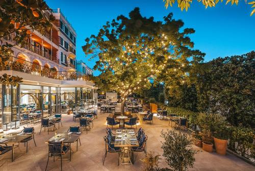 an outdoor patio with tables and chairs and a tree at Hilton Imperial Dubrovnik in Dubrovnik