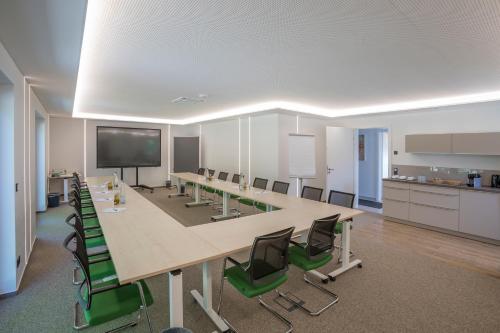 uma sala de conferências com uma mesa longa e cadeiras verdes em Hotel Weiherhof am Golfpark em Wadern