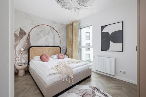 1 dormitorio con 1 cama grande con sábanas blancas y almohadas rosas en Deluxe Apartment Podskale 18 with Parking & Balcony in Kraków by Renters Prestige en Cracovia