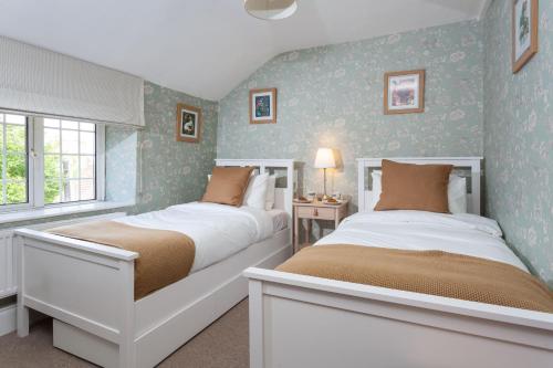 two beds in a small bedroom with blue walls at Hurdler's Cottage in Shipston-on-Stour