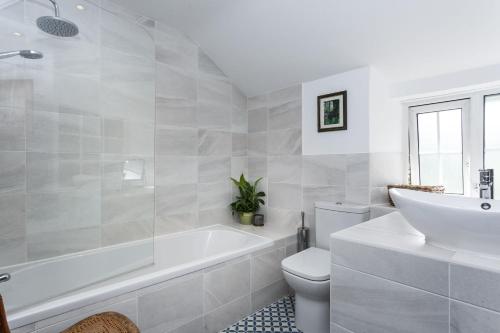 baño blanco con bañera, aseo y lavamanos en Hurdler's Cottage, en Shipston on Stour