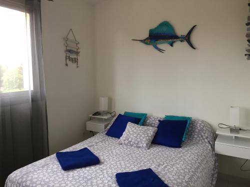 a bedroom with a bed with blue pillows and a fish on the wall at Chambre coquette dans villa proche de la plage in Sète