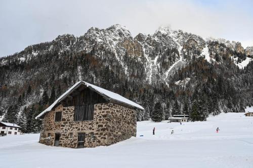 a stone building in the snow in front of a mountain at Rifugio Cereda in Fiera di Primiero