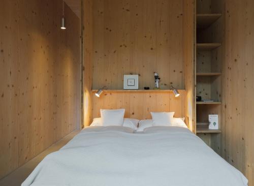 1 cama blanca grande en una habitación con paredes de madera. en quartier - über Nacht in besonderer Architektur, en Garmisch-Partenkirchen
