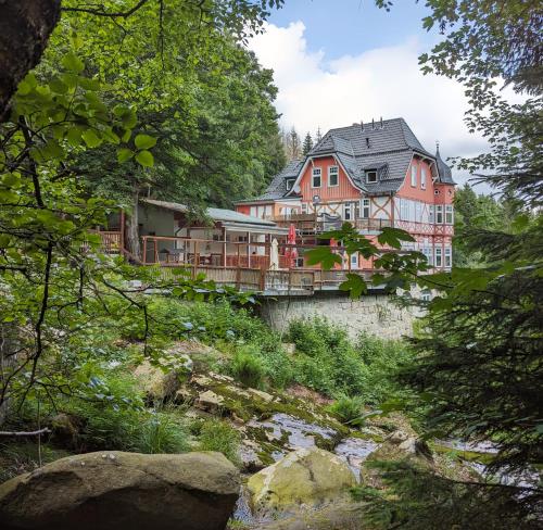 una casa grande en un puente sobre un río en Waldgasthaus & Berghotel Steinerne Renne, en Wernigerode