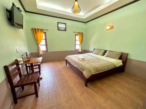 1 dormitorio con cama, mesa y TV en โรงแรมแสงทองรีสอร์ท, en Ban Nam Mong