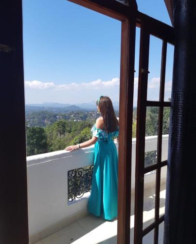 a woman in a blue dress sitting on a balcony at Ceylon Breeze in Kandy