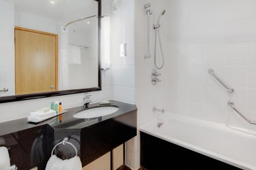 a bathroom with a sink and a shower and a tub at DoubleTree by Hilton Manchester Airport in Hale