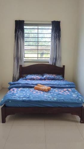 un letto con piumone blu e finestra di Steffan Family Stay a Kampong Teng