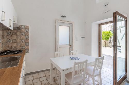 a white kitchen with a white table and chairs at Casa Mimina in Ischia
