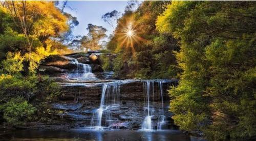 a painting of a waterfall in a river with the sunlight at Treetop Leura Deluxe Family Cabin in Leura