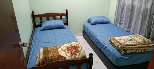 Rumah Inap Bandar Puteri Jaya Sungai Petani في سونغاي بيتاني: سريرين توأم في غرفة نوم مع ملاءات زرقاء