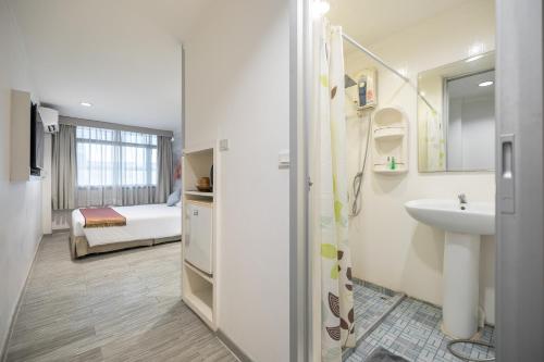 a white bathroom with a sink and a bed at Pratunam City Inn in Bangkok