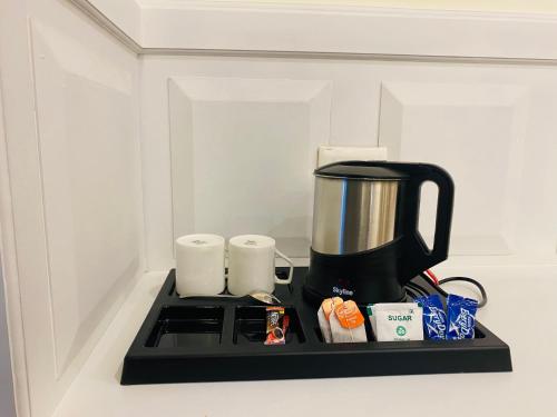 a counter with a coffee maker and cups on it at Blueberry Hotel zirakpur-A Family hotel with spacious and hygenic rooms in Chandīgarh