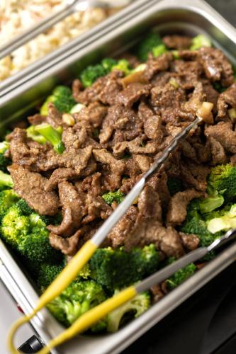a dish of food with beef and broccoli with chopsticks at Omeo Suites in Alhambra