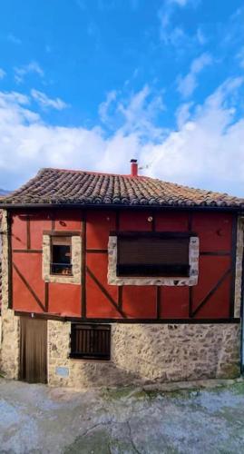 un edificio rojo con ventana y techo en La herradura, acogedora casa en Montemayor del Río, en Montemayor del Río