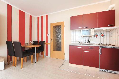 ベンサージールにあるFerienwohnung Inselblickのキッチン(赤いキャビネット、テーブル、椅子付)