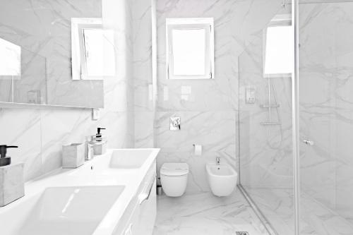 a white bathroom with a toilet and a sink at Piccolo Mondo by CityBookings in Bucharest