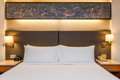 a bed with two white pillows and a painting above it at Chatrium Sathon Bangkok in Bangkok