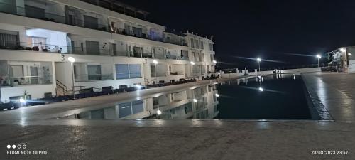a swimming pool in front of a building at night at Adan beach in Aourir