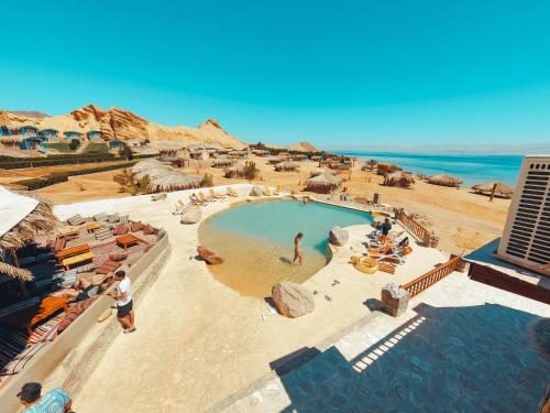 a swimming pool at a resort with people sitting around it at New Moon Island Camp in Nuweiba
