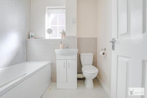 a white bathroom with a toilet and a sink at Silver Stag Properties, 3 BR w Parking and Garden in Smisby