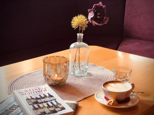 a table with a cup of coffee and a vase at Hotel Alpenland in Moso
