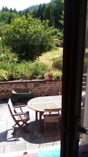 a table and chairs on a patio with a view of a garden at Gîte "À Moussey vous" in Moussey