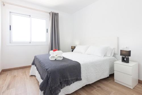 a white bedroom with a bed with two teddy bears on a blanket at Apartamento Vista Atlántico Puerto Rico in Mogán