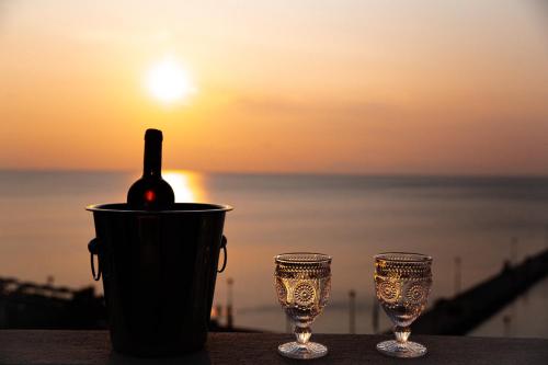 a bottle of wine in a cup next to two glasses at Luxury Plateia Rooms in Perea