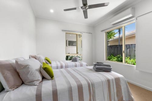 a white bedroom with two beds and a window at Harbour Drive Luxury in Bluewater Estate in Yorkeys Knob