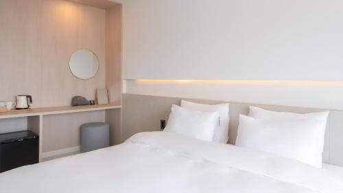 a hotel room with a large bed with white pillows at Geoje Mongdol Beach H Avenue Hotel in Geoje 