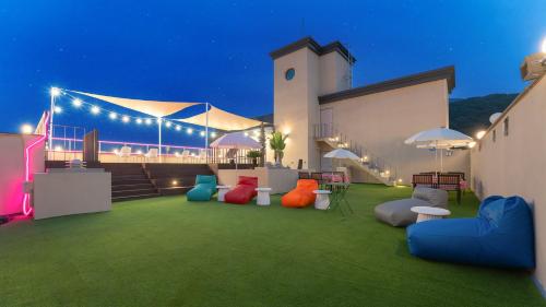 un bâtiment avec une pelouse dotée de chaises et de parasols colorés. dans l'établissement Geoje Mongdol Beach H Avenue Hotel, à Geoje