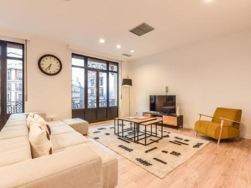 ein Wohnzimmer mit einem Sofa, einem Tisch und einer Uhr in der Unterkunft apartamento en plaza de canalejas in Madrid