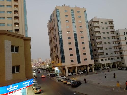 a city street with cars parked in front of tall buildings at personel room for yourself (home) in Sharjah