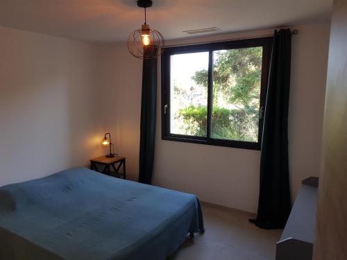 a bedroom with a blue bed and a large window at Maison avec piscine in Vaison-la-Romaine