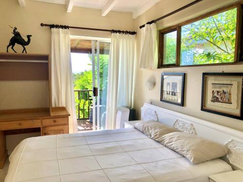 a bedroom with a large white bed and a window at Bushmans River Lodge in Kenton on Sea
