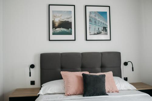 een slaapkamer met een bed met vier foto's aan de muur bij Macao Apartmani in Vinkovci