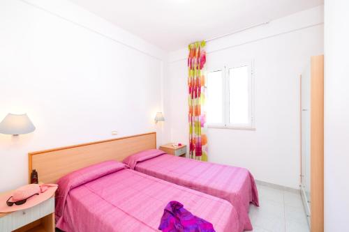 a bedroom with a pink bed with a purple blanket at Baia Degli Aranci Suite & Apartments in Vieste