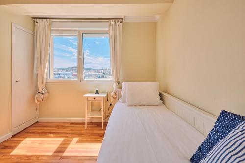 een slaapkamer met een bed en een raam bij Mar de Coroso by Serendipia Turismo in Ribeira