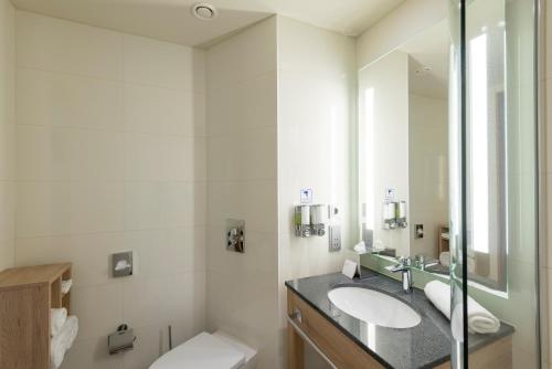 a bathroom with a sink and a toilet and a mirror at Hampton by Hilton Berlin City Centre Alexanderplatz in Berlin